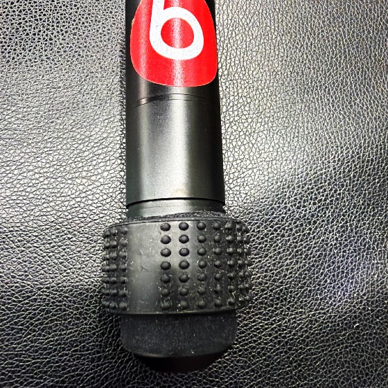 Empuñadura cilíndrica metálica negra con logo Beats